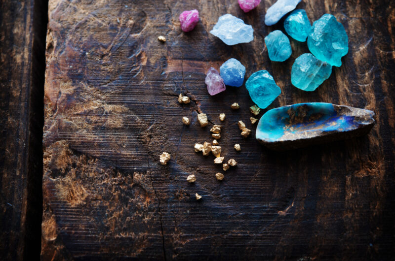 Treasure hunting. Mining for gems. Gold and gems on rough wooden surface.